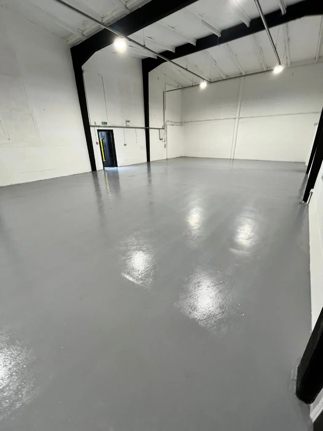 Commercial unit refurbished with white-painted blockwork walls, exposed steelwork and a freshly resin-coated grey floor