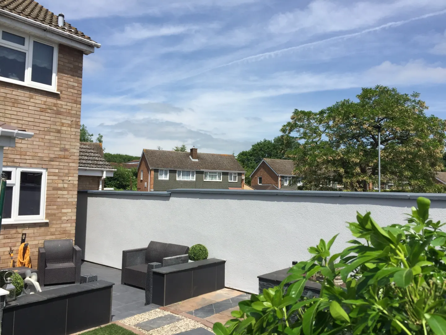 Rendered and painted garden wall with a coping detail, alongside a slate-paved patio seating area