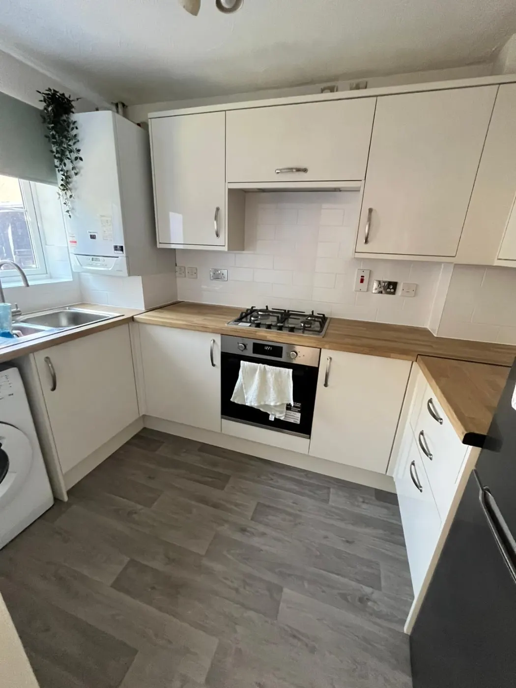 Cream kitchen refit with oak-effect worktops, white metro tiling, new oven and hob, and grey wood-effect flooring