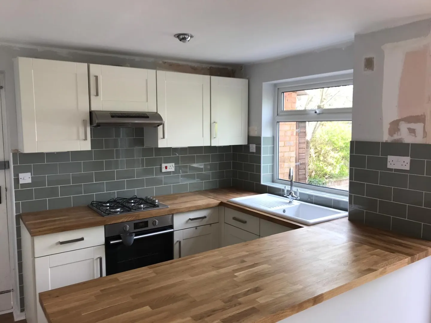 Refitted kitchen with cream shaker doors, solid oak worktops, sage metro tiled splashback and a new gas hob