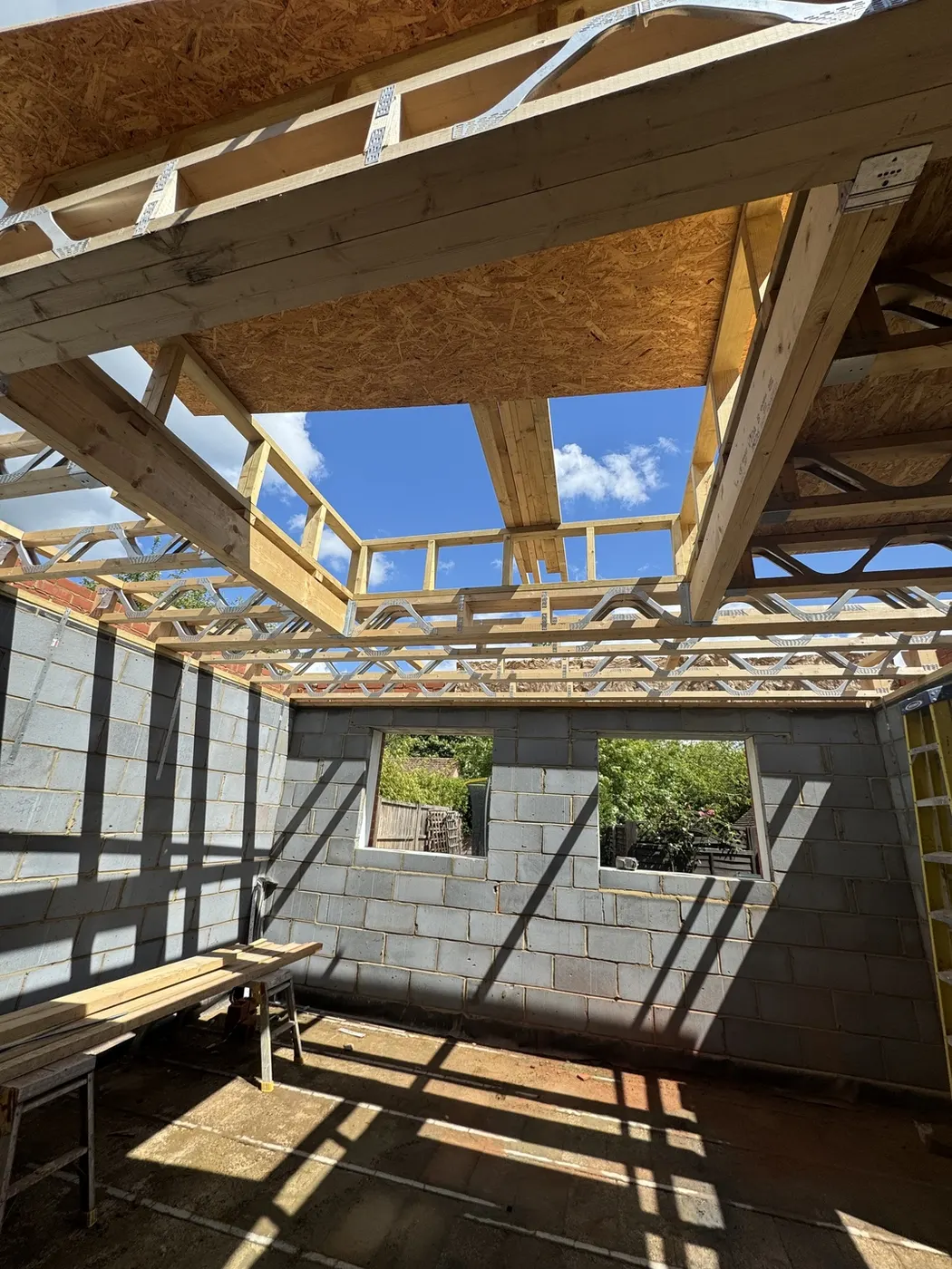 Interior of a new single-storey build showing blockwork walls, engineered floor joists and a framed roof lantern opening